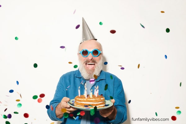 Man wearing party hat and holding birthday cake