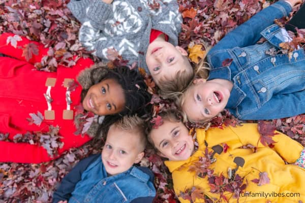 Kids lying on the ground full of leaves