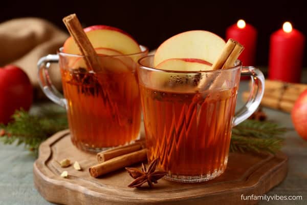 glasses of homemade apple cider with cinnamon sticks and slices of apple