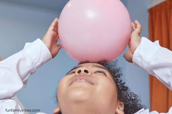 girl putting balloon on top of head