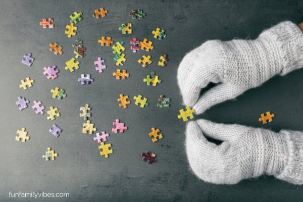 mittened hands trying to assemble a puzzle
