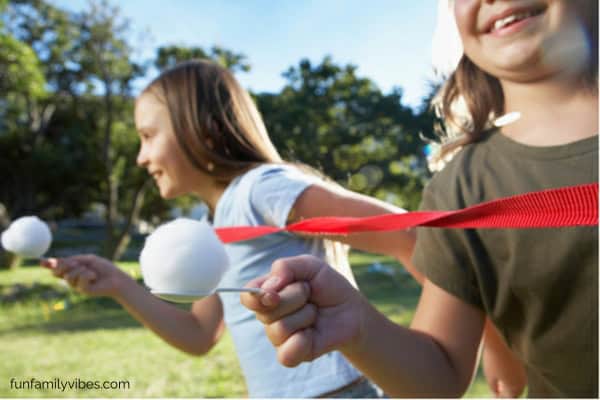 kids holding a spoon with a cotton ball in a race