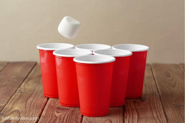 plastic cups and a marshmallow about to fall into a cup