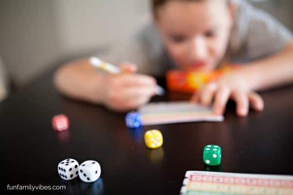 Several dice on the table, girl writing in the background