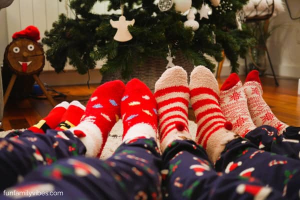 3 pairs of legs wearing maching pajamas and Christmas socks
