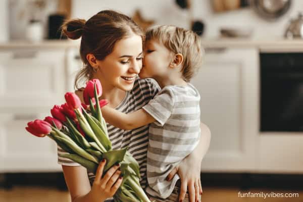 Little boy kissing his mother and giving her flowers on Mother's day