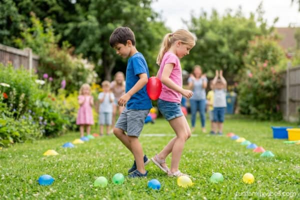 2 kids back to back with a balloon sandwiched between their backs, other kids cheering on