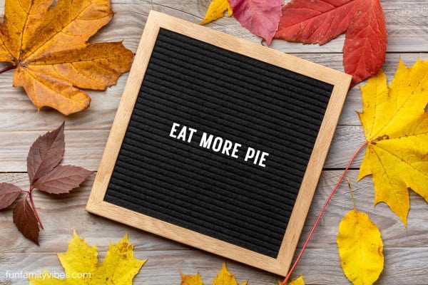 Letterboard with friendsgiving saying on wooden table with fall leaves